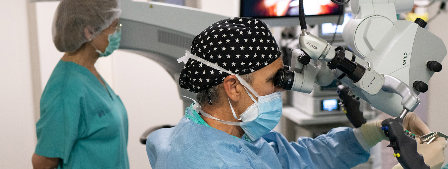 El Dr. Alfredo Rigau Llauger realizando una operación quirúrgica otorrinolaringólogica en la garganta con la ayuda de un microscopio